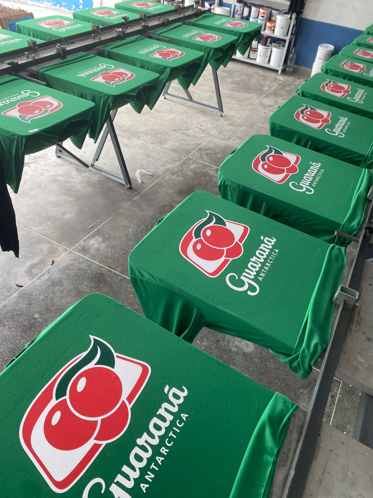 Camisetas Guaraná Antarctica na prensa de serigrafia — produção em lote na Veloz Uniformes